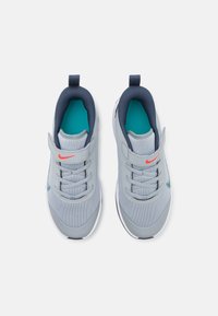 Gray athletic shoes with mesh upper, navy accents, turquoise lining, and a red logo. Features single velcro strap and traditional laces.