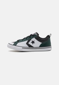 Zapatillas verdes y blancas con acentos negros, parte superior texturizada, suela plana, que presentan un logo de estrella y cordones negros. Diseño clásico de corte bajo.