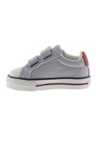 Sneaker grigia in tela con due straps in velcro, punta in gomma bianca e un accent rosso sul tallone. Presenta una parte superiore testurizzata e una suola resistente.