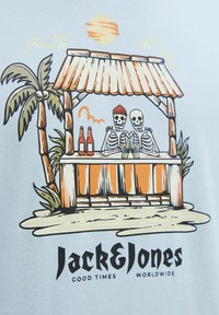 Lichtblauw t-shirt met een afbeelding van een tiki bar met twee skeletten, palmbomen en flessen. Onder de afbeelding staat de tekst "Jack & Jones."