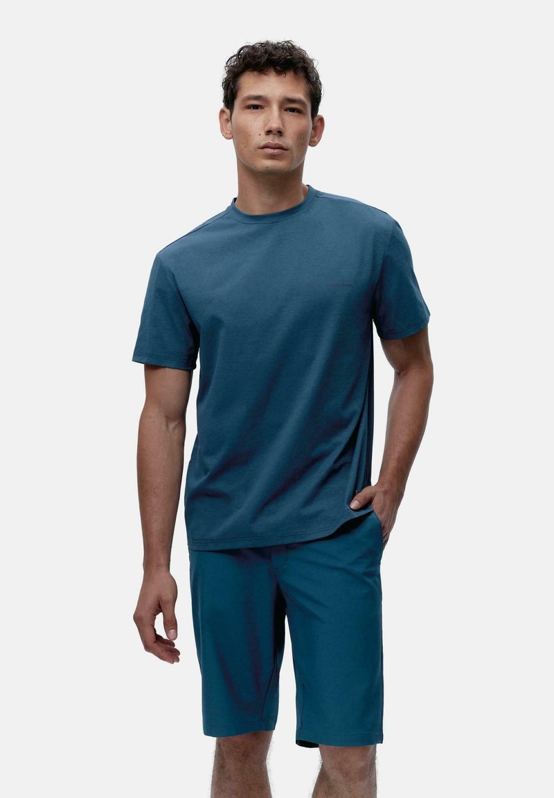 Męski strój składający się z niebieskiej koszulki z okrągłym dekoltem oraz dopasowanych szortów, oba wykonane z lekkiego materiału o gładkiej teksturze.