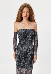 Abito midi off-the-shoulder in rete trasparente con motivi floreali e di testo in nero e grigio, caratterizzato da maniche lunghe e dettagli arricciati in vita.