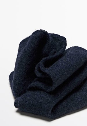 Coperta di lana blu navy, spessa e morbida al tatto, piegata con bordi irregolari. Superficie liscia con una leggera lucentezza e un aspetto accogliente.