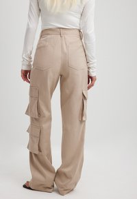 Beige cargobroek met een relaxte pasvorm, voorzien van zijzakken, een hoge taille en dubbele achterzakken. Gemaakt van een gestructureerde stof.