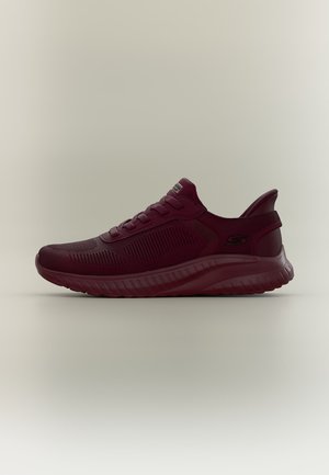 Basket de sport rouge foncé avec tige en tissu texturé, fermeture à lacets, semelle rembourrée et logo Skechers sur le côté.
