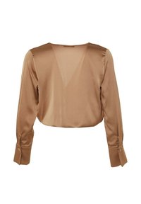 Brun satinbluse med dyb V-ryg, lange ærmer og knaplisser. Stoffet har en glat, blank tekstur og kort design.