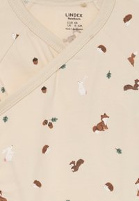 Light beige wrap top featuring a printed design with small animals (rabbits, squirrels, hedgehogs) and acorns, accented with green leaves.