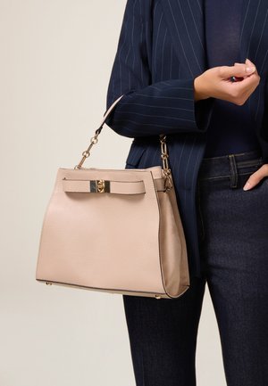 Torebka skórzana w kolorze brzoskwiniowym z fakturą, z detalem w postaci kokardy, złotymi elementami oraz krótkim paskiem, charakteryzująca się usztywnionym kształtem i kontrastującym czarnym brzegiem.