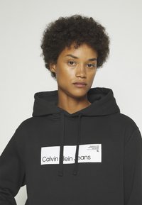 Calvin Klein Jeans HYPER REAL BOX LOGO GENDERLESS UNISEX - Jersey con capucha - black