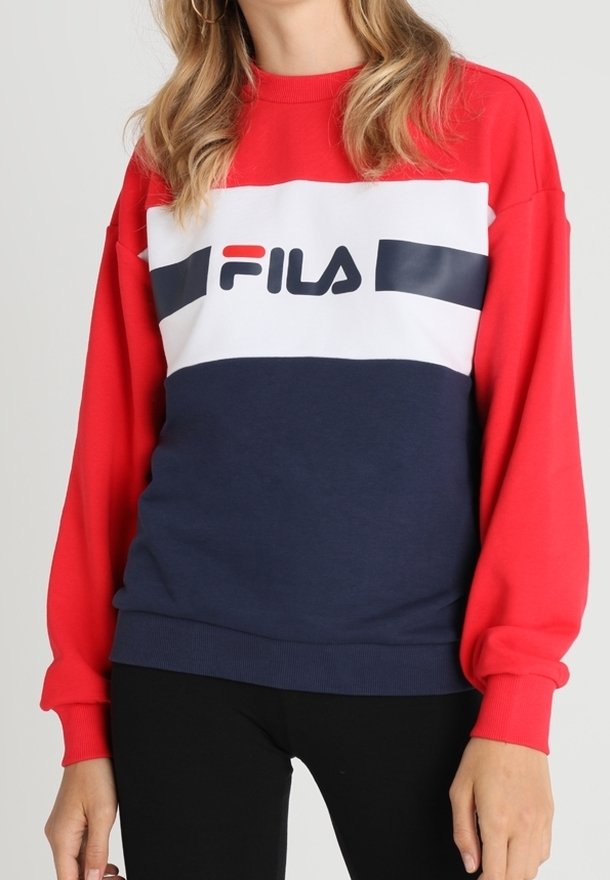 Sudadera en rojo y azul marino con mangas largas, que presenta una banda blanca en el pecho con el logo de "FILA" en negro. Diseño atlético clásico.