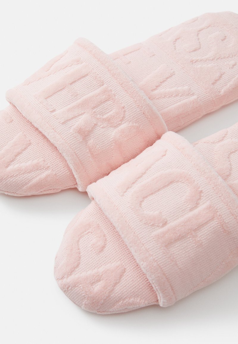 Pantofole scivolose in spugna rosa con testo stampato sulle cinghie. Texture morbida, punta arrotondata e soletta imbottita per il comfort.