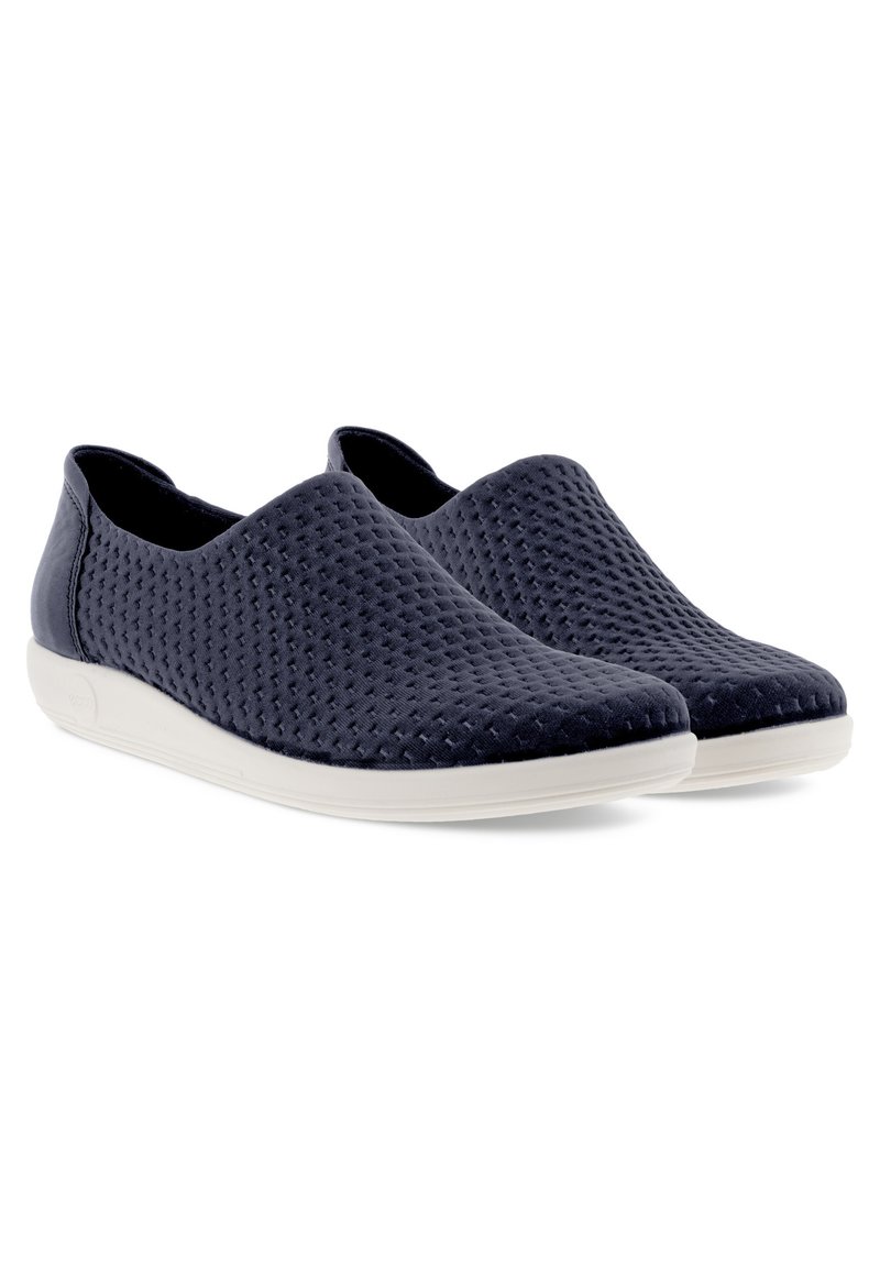 Granatowe buty slip-on z fakturowanym, perforowanym wierzchem. Podeszwa jest biała, co stanowi kontrastujący akcent.