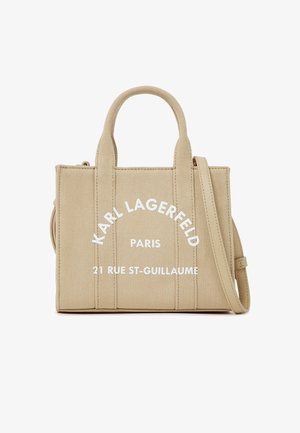 Bolsa de tela beige con dos asas, correa de hombro desmontable y texto blanco "Karl Lagerfeld Paris 21 Rue St-Guillaume" en el frente.