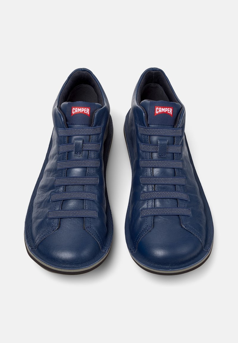 Marineblauwe sneakers met een afgeronde neus, voorzien van een gestructureerde afwerking, zes veterogen en een prominent "CAMPER" logo op de tong.