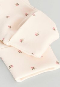Ljust rosa tyg med en strukturerad yta, prydnad med ett blommönster av små rosa rosor och gröna blad, vikt med en mjuk finish.