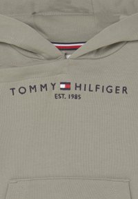 Felpa verde con cappuccio e tasca a marsupio, con logo ricamato "TOMMY HILFIGER" e data di fondazione 1985 in blu navy.
