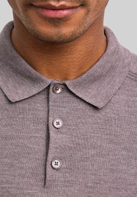 Szara koszulka polo o miękkiej fakturze, z szpiczastym kołnierzykiem, zapinana na trzy guziki, z delikatnymi przeszyciami.