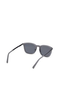 Lunettes de soleil à monture rectangulaire grise avec verres teintés foncés et branches noires fines, présentées sous un léger angle sur fond blanc.
