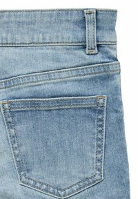 Svijetloplave traperice s pet džepova, vidljivim šavovima i teksturiranom površinom, s uobičajenim pojasom i stražnjim džepom.