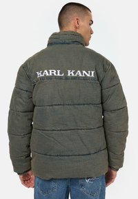 Zöld puffermellény steppelt textúrával, magas gallérral és fehér hímzésű "KARL KANI" felirattal a hátsó részen. Formázott mandzsetta.