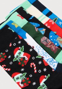 Krāsainas zeķes ar dažādiem svētku motīviem, tostarp varoņu attēliem, sniegpārsliņām un konfekšu nūjām uz dažādiem fona.