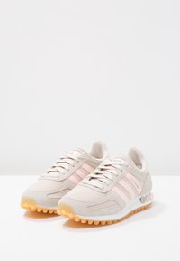 Béžové sportovní boty z kombinace síťoviny a semiše, se zajímavými růžovými detaily a třemi pruhy, gumovou podrážkou s texturovaným gripem a polstrovaným límcem.