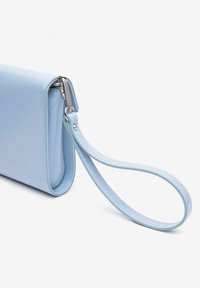 Lichtblauwe gepatineerde leren clutch met een plat ontwerp, een afneembare polsband en een zilveren ritsaccent. Gladde textuur en minimalistische stijl.