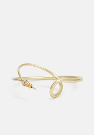 Bracciale in metallo color oro con un design fluido e curvilineo. Presenta un piccolo e prominente accento color argento a un'estremità.