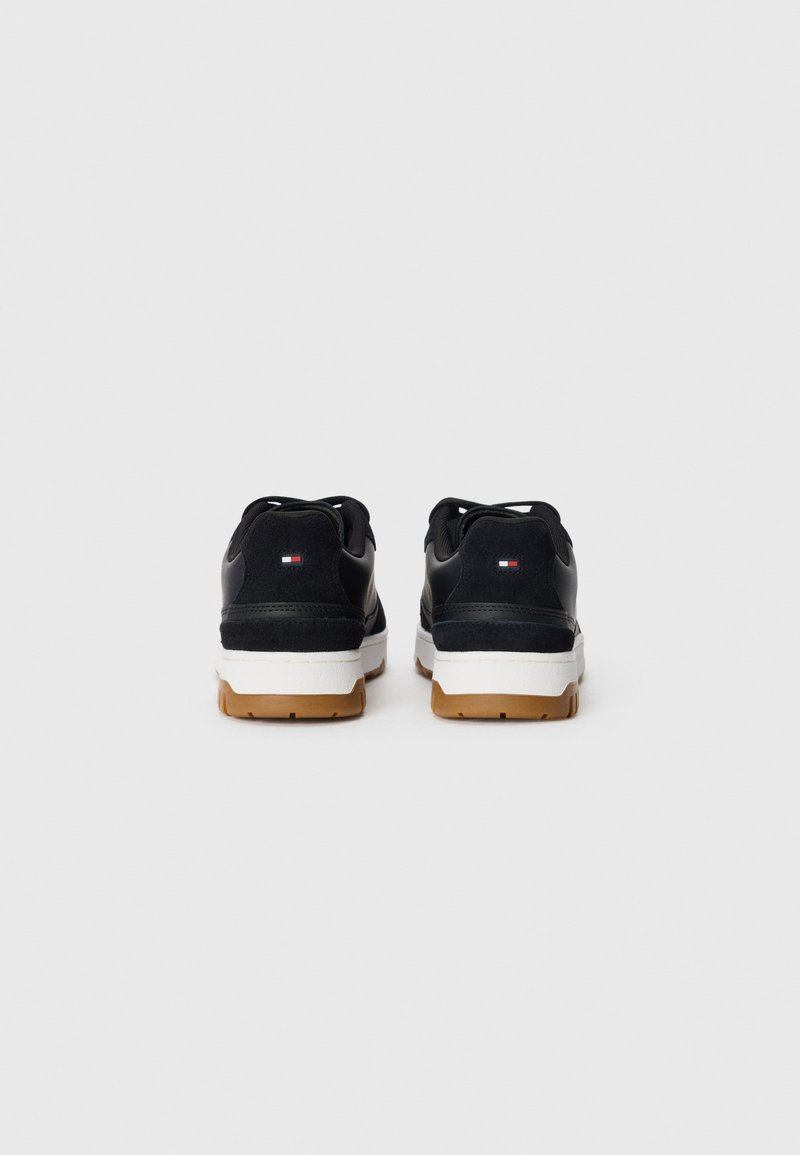 Schwarze Sneakers aus Wildleder und synthetischen Materialien, mit weißer Zwischensohle und Gummisohle. Mit minimalem Branding an der Ferse.