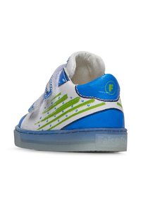Sneaker bianco con accenti blu e verdi, caratterizzato da una texture liscia, fibbia in velcro e elementi di design a pois. Suola in gomma trasparente.