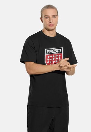 Czarna koszulka z krótkim rękawem z czerwonym herbem i napisem "PROSTO" oraz znakami plus ułożonymi w siatkę. Wykonana z bawełnianej tkaniny.
