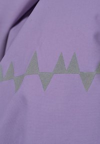 Lila tyg med en texturerad yta som har ett zick-zackmönster i grått, som växlar i höjd och skapar visuell intresse.