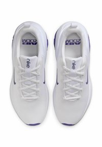 Zapatillas deportivas blancas con parte superior de malla, acentos morados en el talón y el logo, diseño de cordones y lengüeta acolchada para mayor comodidad.