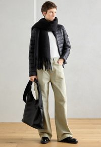 Juodas pūkinis švarkas, balta palaidinė, per dideli smėlio spalvos džinsai, juodas šalikas su kutais ir juoda rankinė. Lygūs tekstūros, laisvas siluetas.