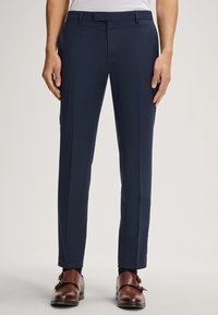 Marineblauwe dress pants in een getailleerde pasvorm, gemaakt van gladde stof, met een vlakke voorkant, riemlussen en minimale zichtbare naden. Accessoires zijn bruin schoenen.