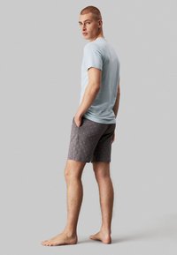 Light blue cotton t-shirt paired with gray patterned shorts. The shorts feature a subtle print, side pockets, and a casual fit. Socks not worn.