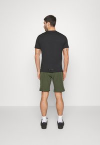 Camiseta negra de manga corta, pantalones cortos deportivos verdes, zapatos negros, calcetines blancos, diseño sencillo, minimalista con poca marca en el dobladillo de la camiseta.