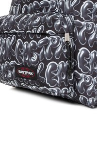 Mochila negra con un patrón abstracto blanco brillante, bolsillo con cremallera y un parche con el logo rojo de Eastpak en la parte frontal.