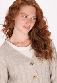 Cardigan tricotat de culoare gri deschis, cu un model în cabluri, având un decolteu adânc în formă de V și două butoane mari de culoare bej. Textură moale și croială lejeră.