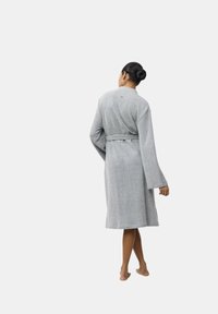 Accappatoio grigio, lungo fino al ginocchio, con maniche lunghe, tessuto texturizzato, vita con cintura e un design minimalista, visto da dietro.