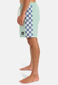 Mentolové plavky s modro-bielou šachovnicovou bočnou časťou, elastickým pásom a malou nášivkou pri leme.