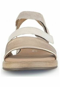 Sandali marroni chiari con accenti metallici dorati, cinturini larghi e un design con punta aperta. Suola con texture in legno e un aspetto minimalista.