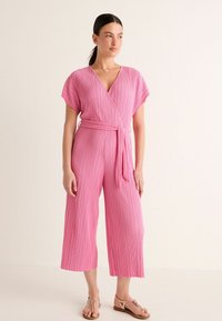 Rosa, kortärmad jumpsuit med inslag av knytning, plisserad textur och knytning i midjan, med breda, kapade ben och djup V-ringning.