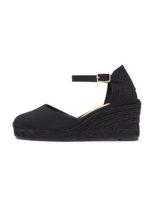 Espadrille noire à talon compensé avec bride de cheville et boucle, talon plateforme tissé texturé, bout fermé, et dessus en tissu.