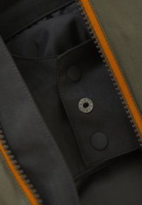 Interno di una borsa in tessuto grigio con trama a spina di pesce, zip arancione e chiusure a pulsante e bottone nere. Fodera liscia in una tonalità più scura.