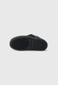 Zwarte suède sneaker met een textuur rubberen zool; beschikt over een zigzagloopprofiel en gegraveerde logo-details.