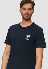 Granatowy bawełniany t-shirt z żółtym haftowanym rysunkowym charakterem na lewej piersi. Okrągły dekolt i krótkie rękawy.