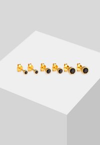 Goldfarbene Steckerohrringe mit drei Paaren in verschiedenen Designs, darunter Tierformen und runde schwarze Steine.