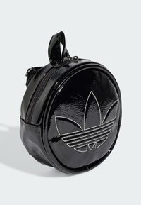 Borsa circolare nera realizzata in materiale sintetico lucido, con un logo in evidenza e cuciture bianche, dotata di chiusura con zip.