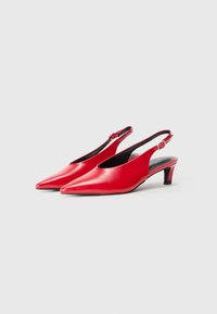 Chaussures slingback en cuir rouge avec un nez pointu et un talon fin. Caractéristiques d'une fermeture à boucle et d'une texture lisse et brillante.